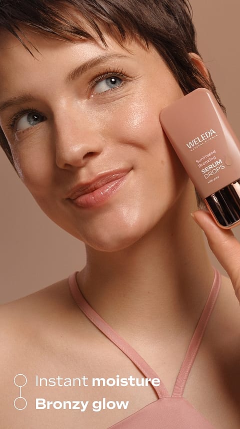 Tjej håller upp Weleda Sunkissed Bronzing Serum Drops mot ansikte
