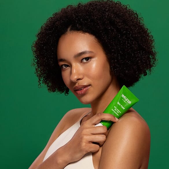 Tjej håller i en tub Weleda Skin Food 75ml