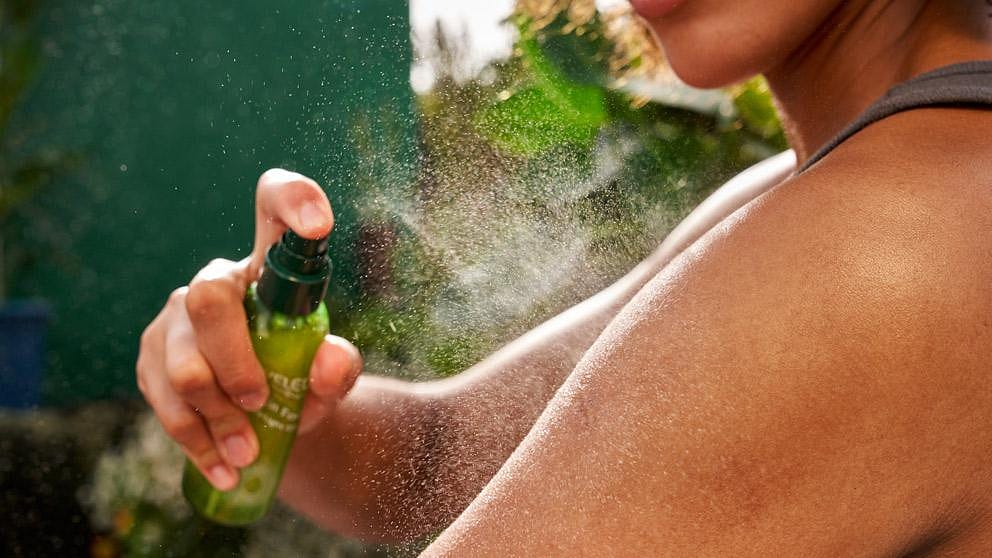 Kvinna sprayar Weleda skin food dry oil på armen