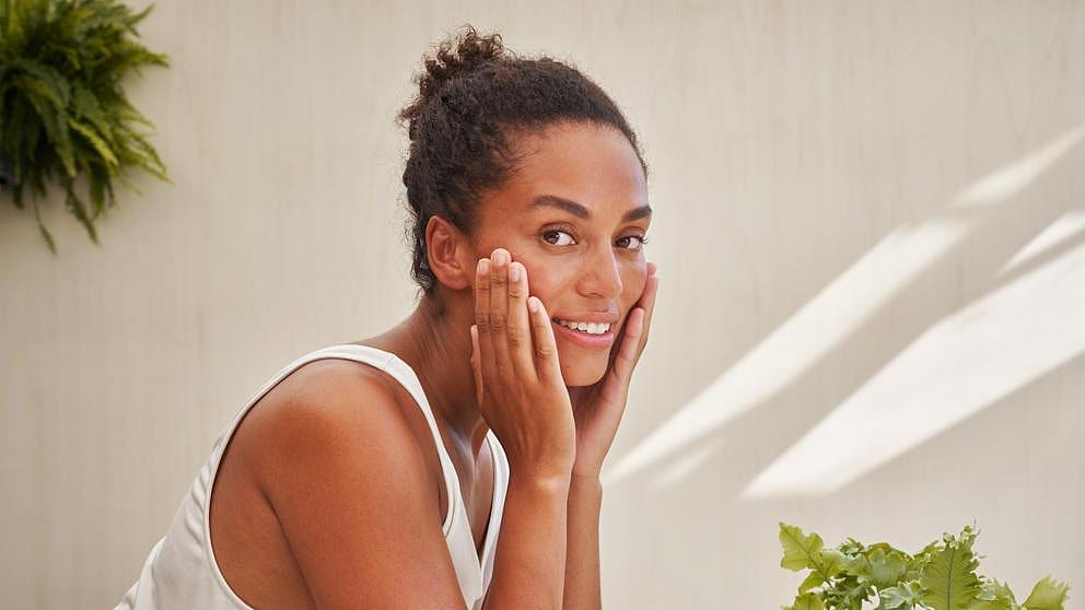Kvinna tvättar ansiktet med Weleda Skin Food Nourishing Cleansing Balm